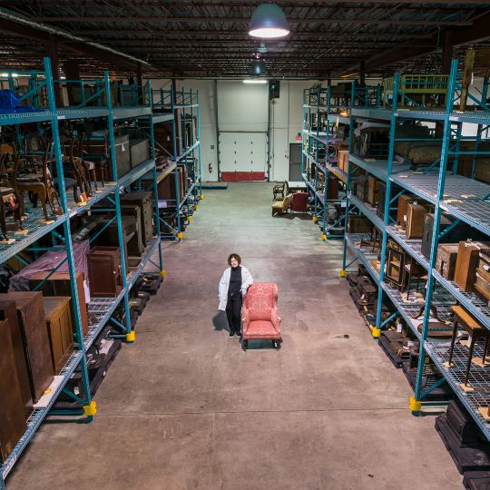 Interior photo of the Parks Canada artefact collection storage, and a collections officer handling artefacts.